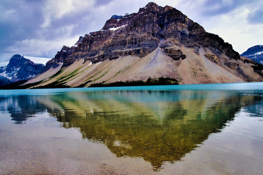 reflection of green mountain on body of water