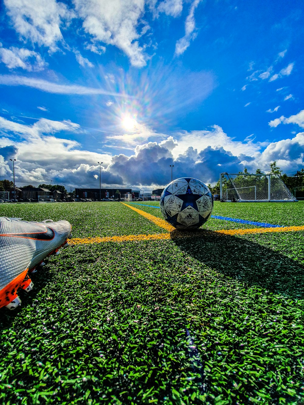 balón de fútbol azul y gris en campo verde bajo cielo blanco y azul durante el día