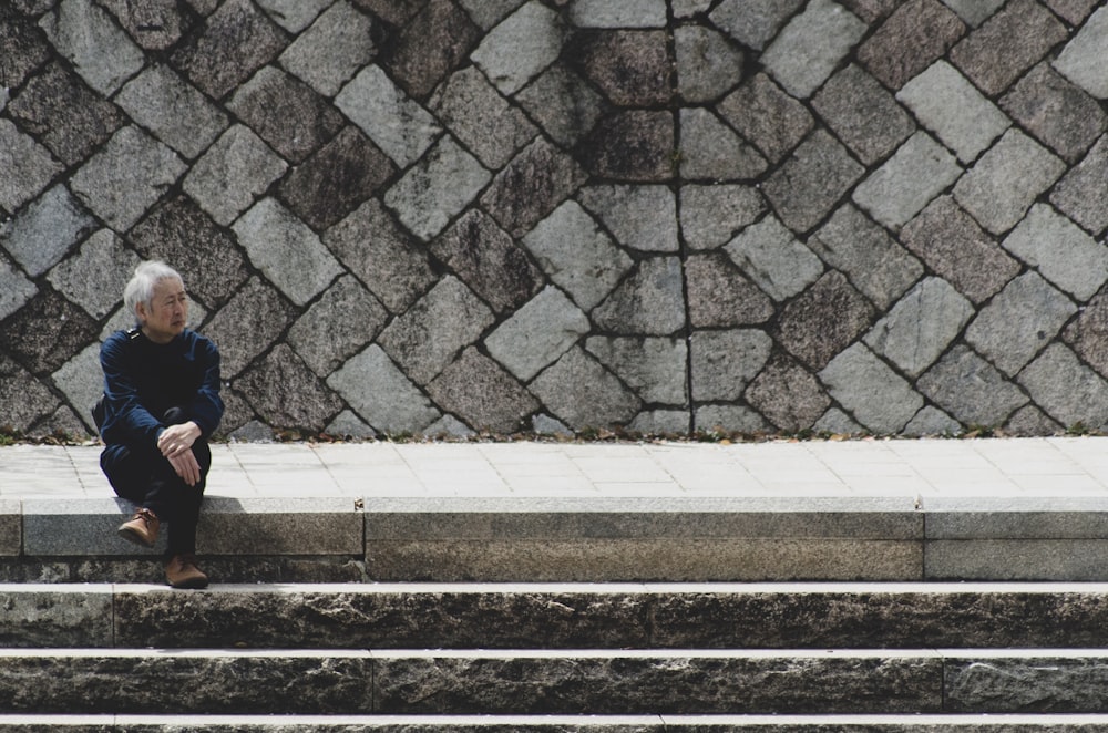 man sitting on stairway near outdoor during daytime