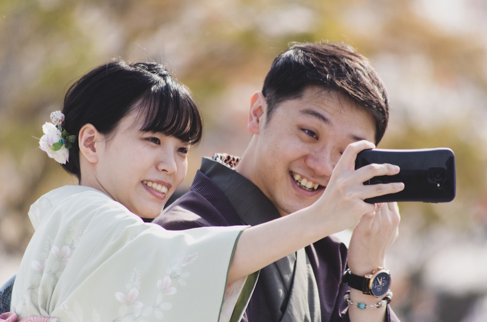 selective focus photography of man and woman taking selfie near outdoor during daytime