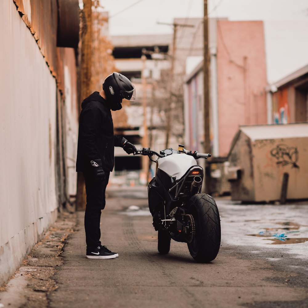 person wearing motorcycle helmet standing near motorbike