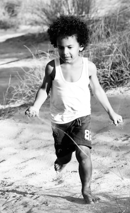 Children playing barefoot in grass near their green school in South Africa