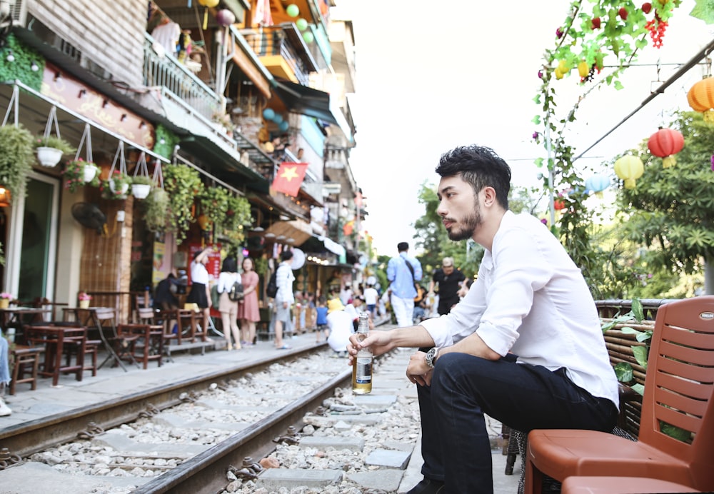 man in white dress shirt sitting on red chair during daytime