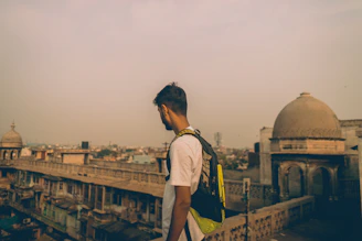 A traveler with a backpack admiring an ancient historic cityscape at dawn.