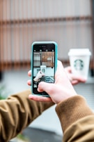 person taking photo of Starbucks cup