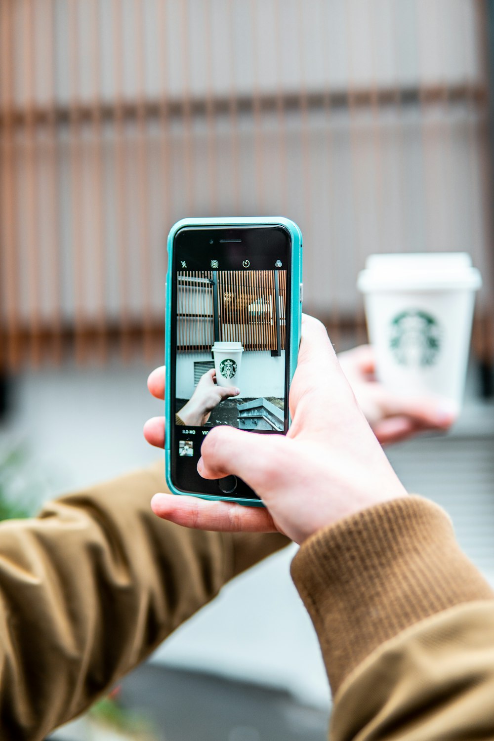 person taking photo of Starbucks cup