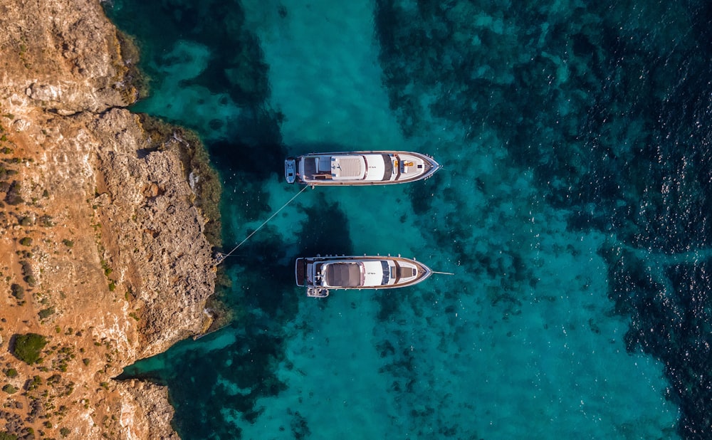 two white boats on teal water at daytime