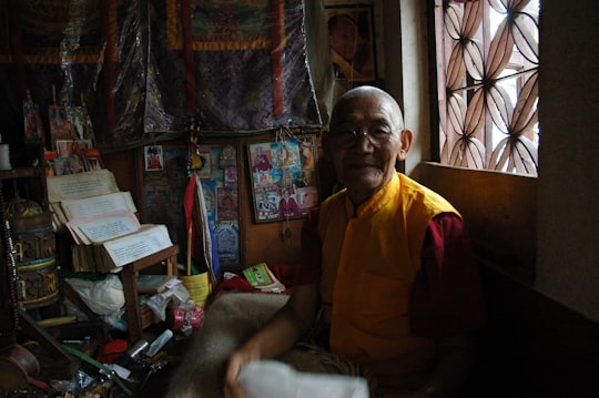 man wearing red top sitting inside house in Pharping Nepal