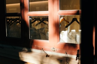Casual tees and dresses hanging in soft natural light near a window.