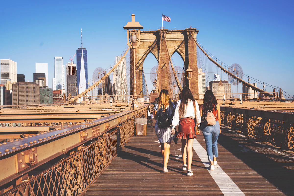 Yaz gününde New York'taki Brooklyn Köprüsü'nde birlikte yürüyen üç genç kadın