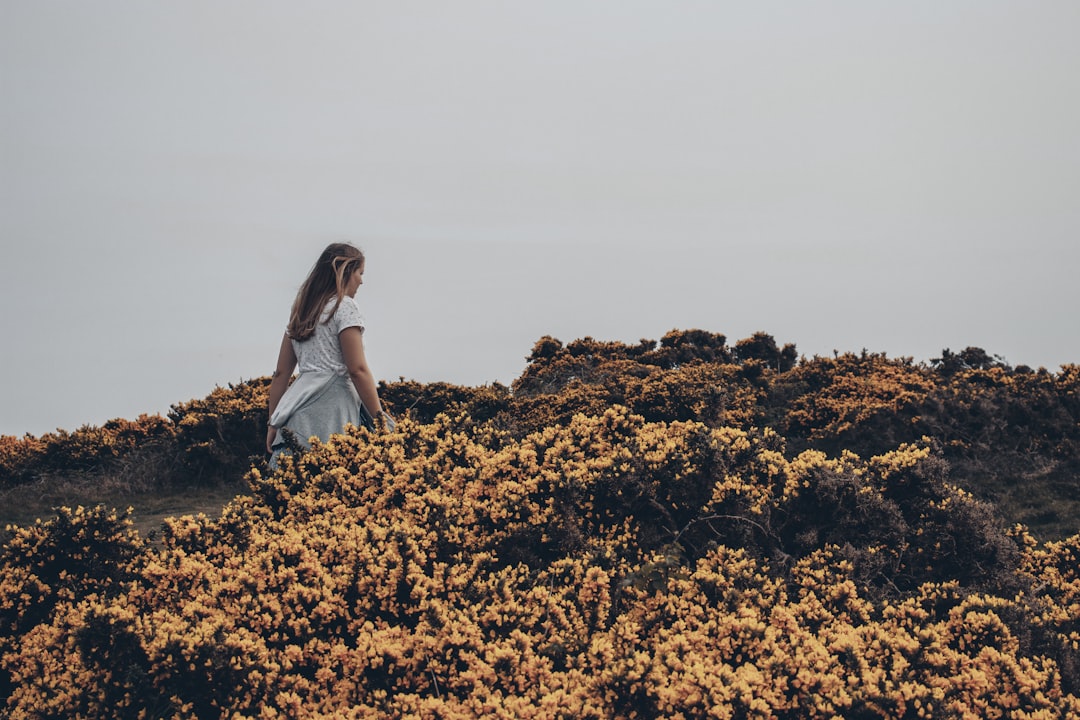 woman in white dress near yellow flowers