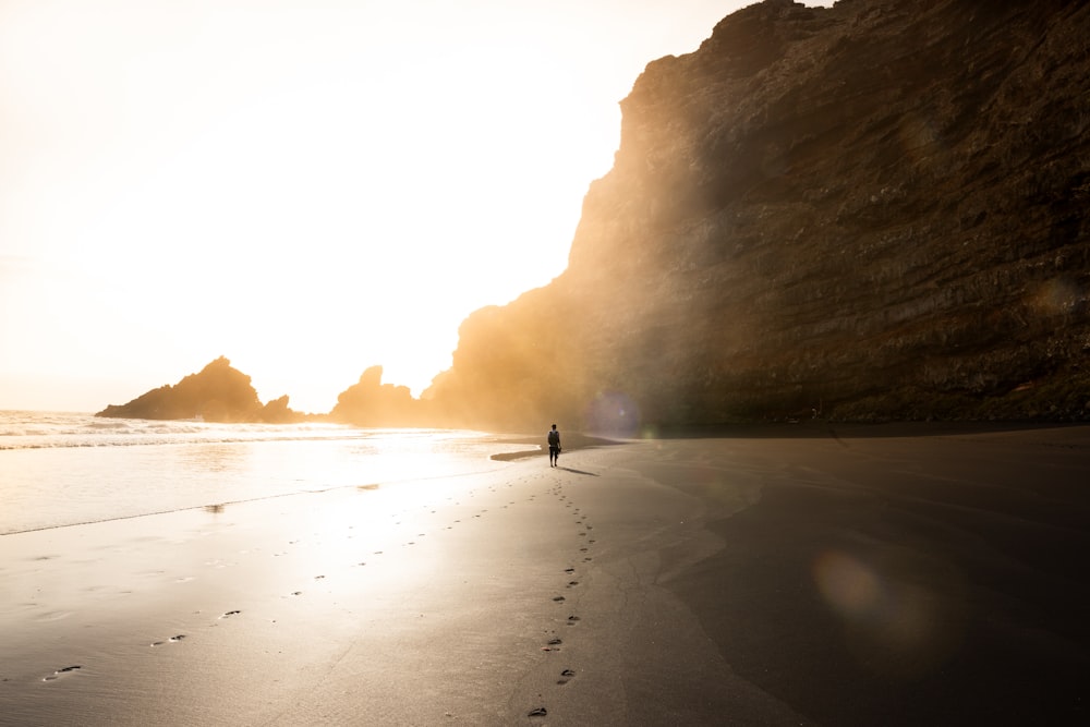 Homme sur le rivage près d’une formation rocheuse