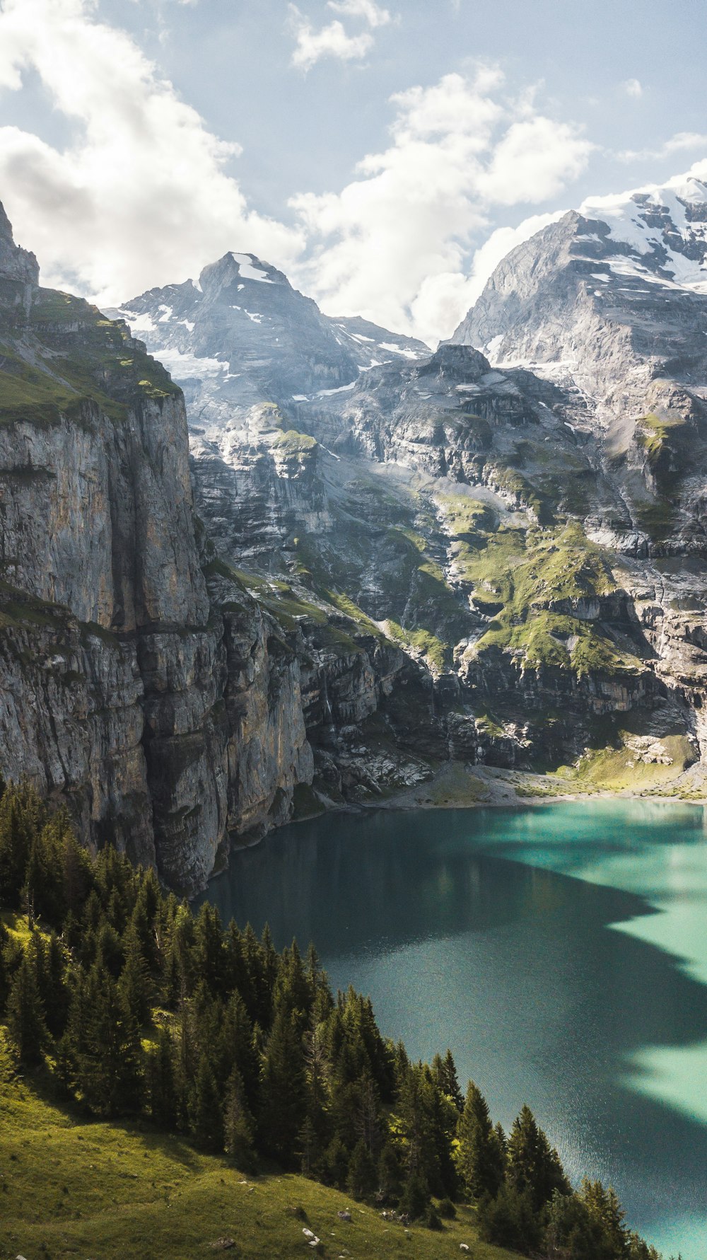 a lake surrounded by mountains and trees on a sunny day