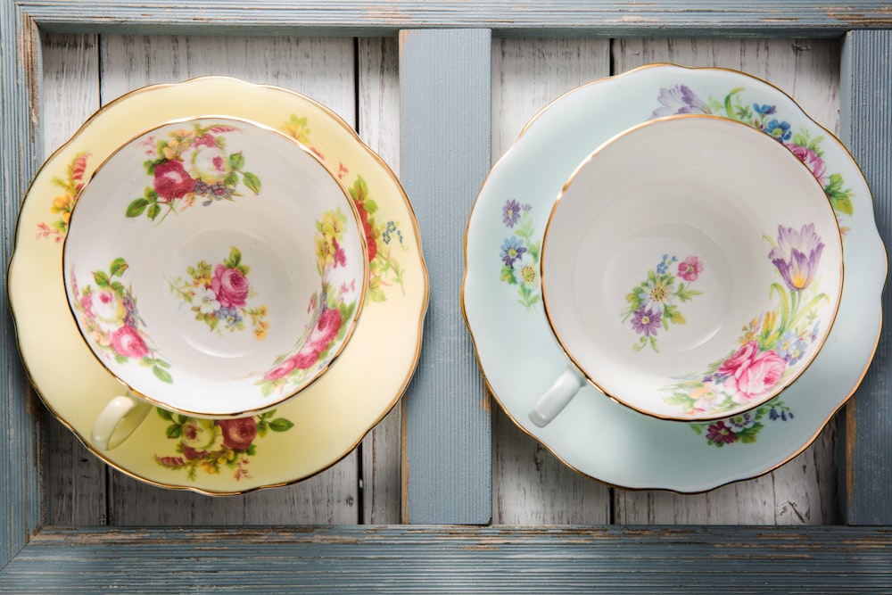 two white-red-and-green floral cups on saucers