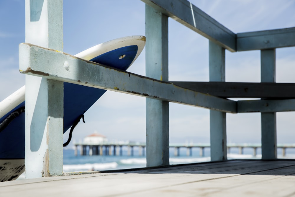 surfboard leans on blue handrail at the beach