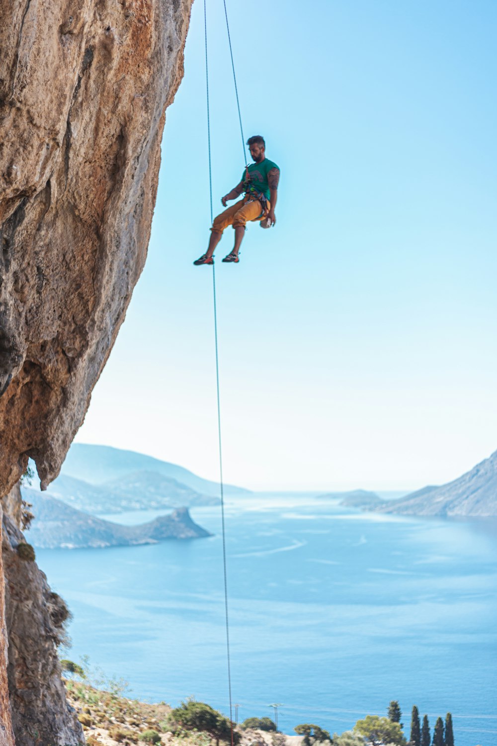 Man hanging on rope on cliff during daytime photo – Free Blue