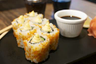 A close-up of soy sauce with wasabi and pickled ginger on the side.