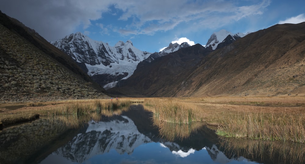 body of water viewing mountain under white and blue sky during daytime