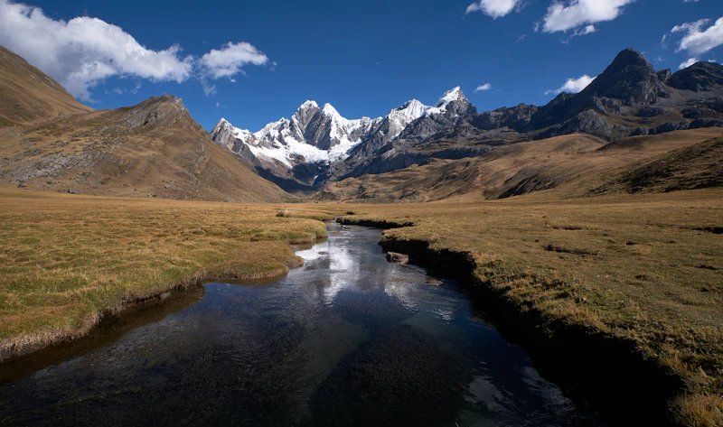 Remote glaciated Andean peaks rising above a river-cut valley in the Peruvian cordillera