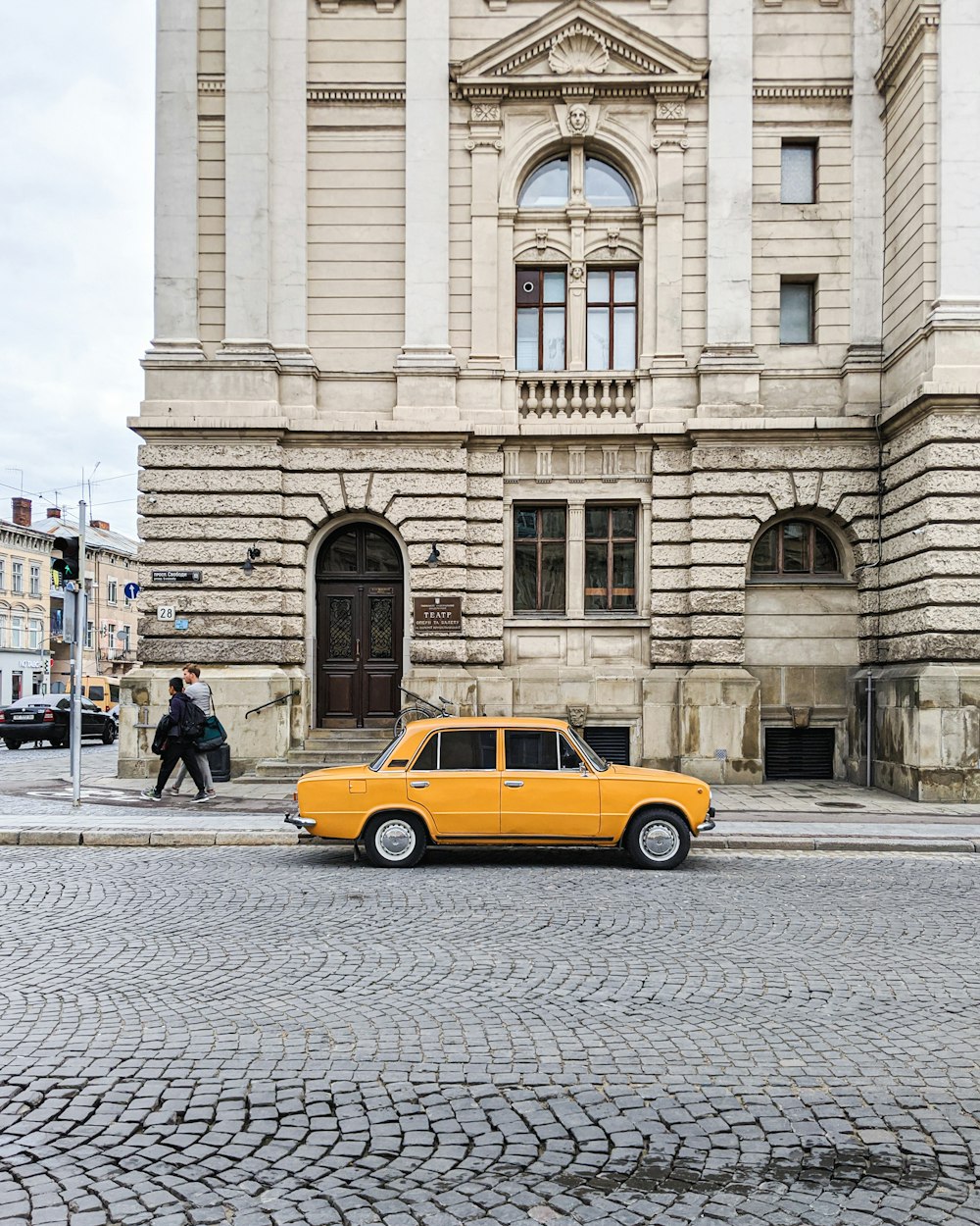 sedã amarelo estacionado ao lado de prédio de concreto