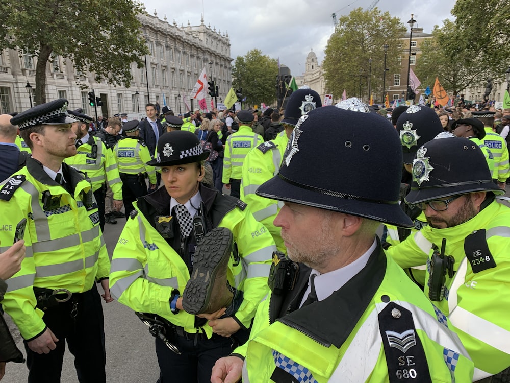 crowd of police officers near people on street beside buildings during daytime