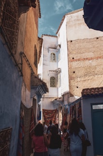 people walking between brown and white concrete houses