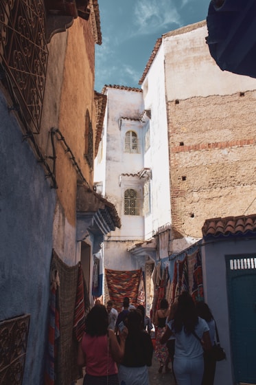 people walking between brown and white concrete houses