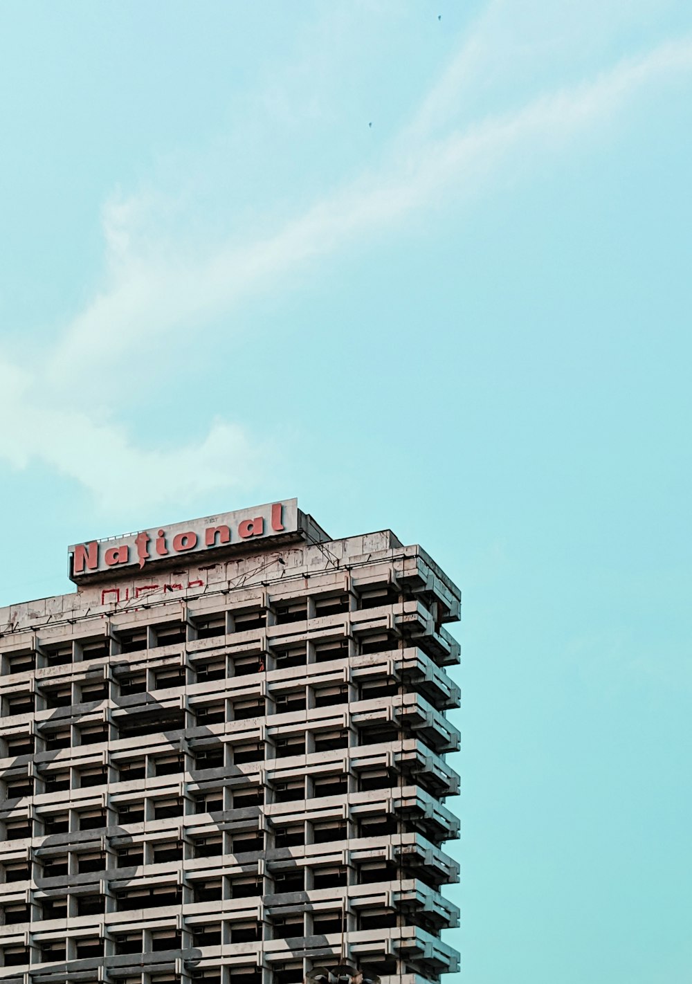 Edificio de varios pisos de hormigón gris bajo un cielo azul tranquilo