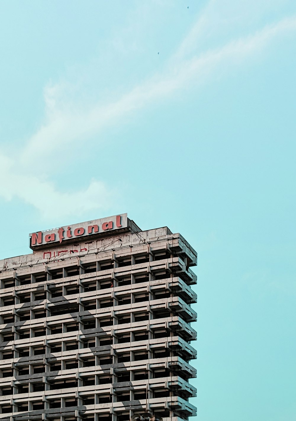 Bâtiment de plusieurs étages en béton gris sous un ciel bleu calme