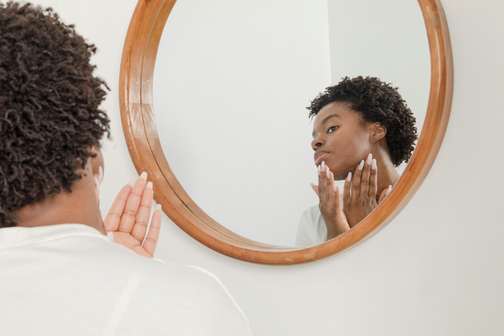 woman looking at skin in a mirror
