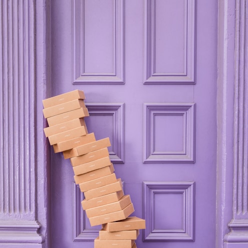 pile of brown boxes beside purple wooden wall