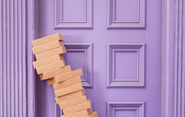 pile of brown boxes beside purple wooden wall