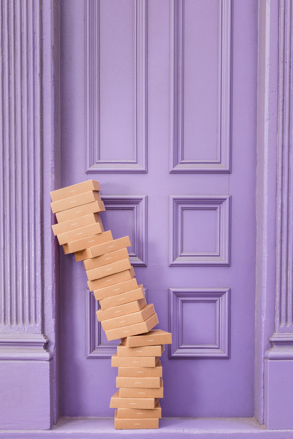 Pila de cajas marrones junto a la pared de madera púrpura