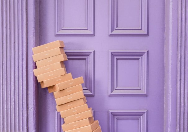 pile of brown boxes beside purple wooden wall