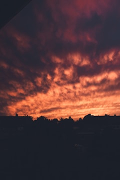 An artistic shot of clouds glowing red above a quiet town.