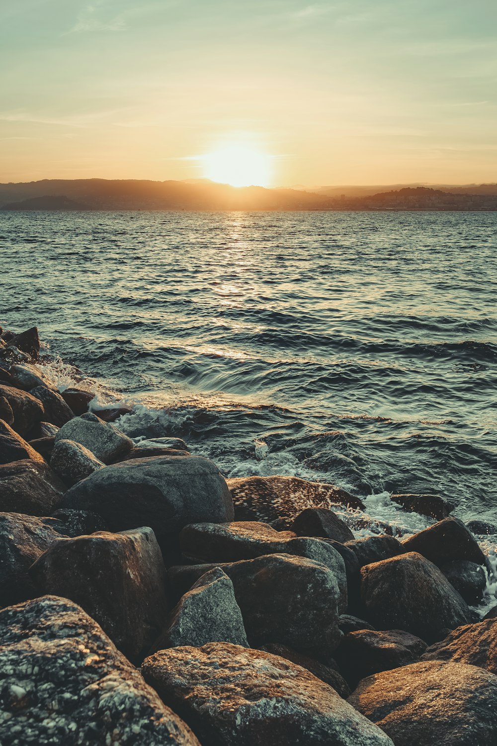 waves splashing on rocks by the seashore during golden hour