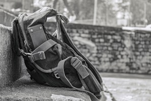 A sleek, durable travel backpack resting on a wooden bench with a scenic mountain trail in the background.