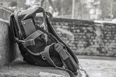 A sleek, sturdy travel backpack resting on a wooden bench with a scenic mountain background.
