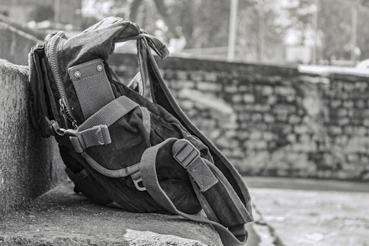 A sturdy black backpack resting on rocky terrain with a mountain backdrop.