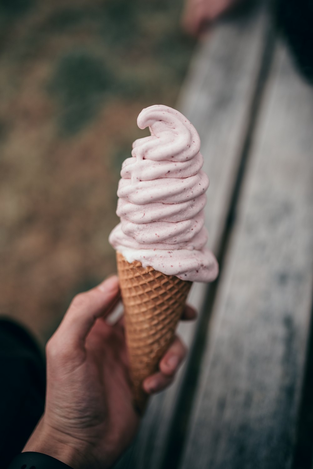 Fotografia a fuoco selettiva della persona che tiene il cono del gelato