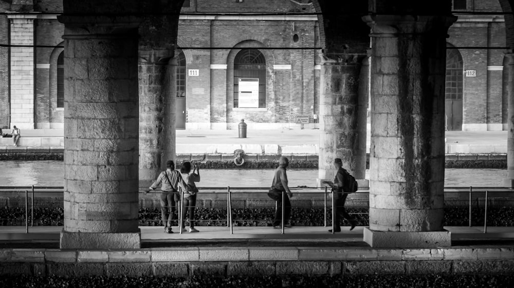 four persons under the bridge in monochrome photo