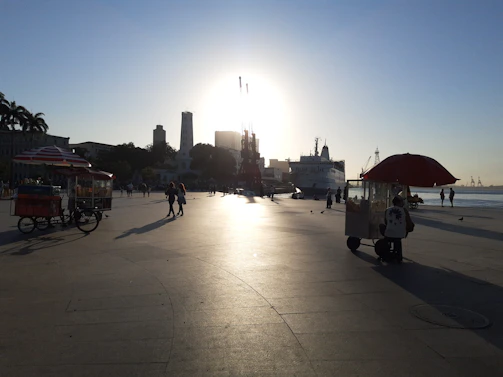 Sunset view of Veracruz's bustling malecón with colorful boats and lively street vendors.