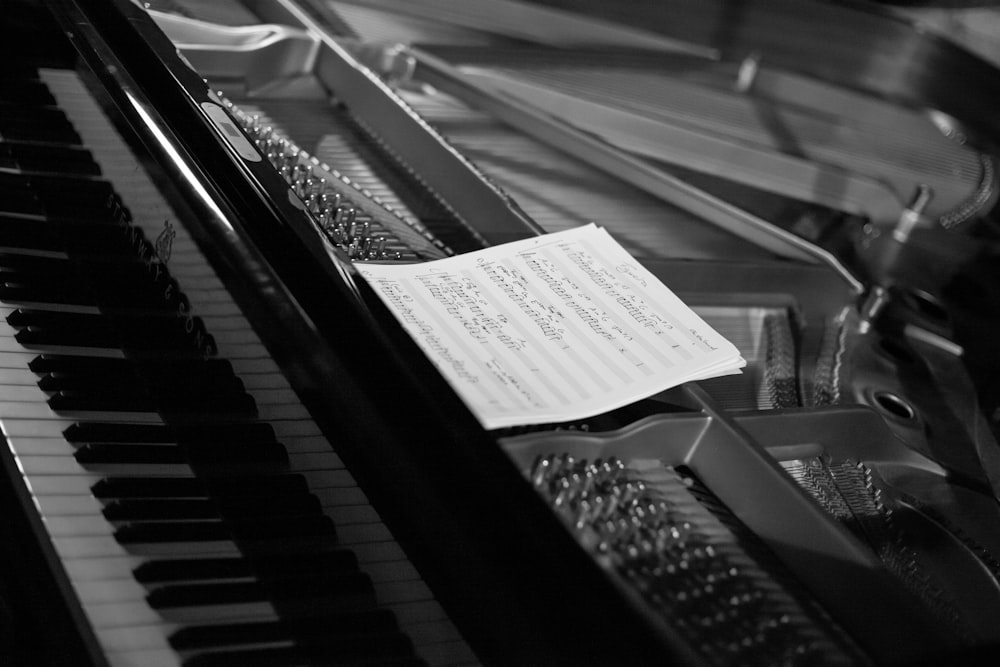 grayscale photography of music sheet on a piano