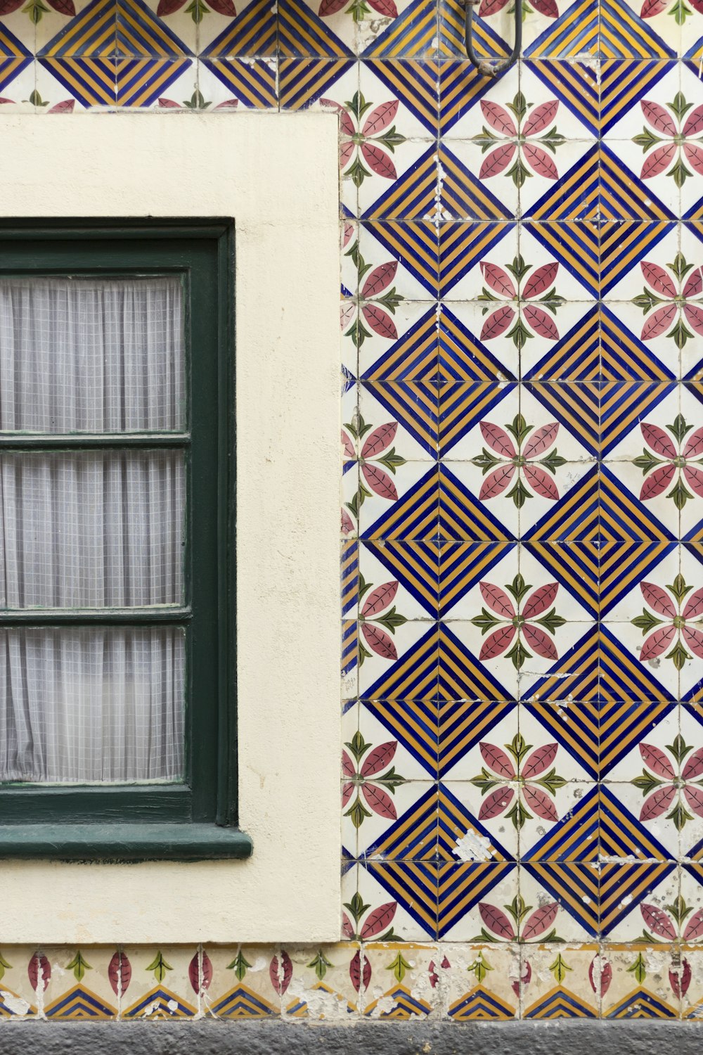 a window with a curtain in front of a tiled wall