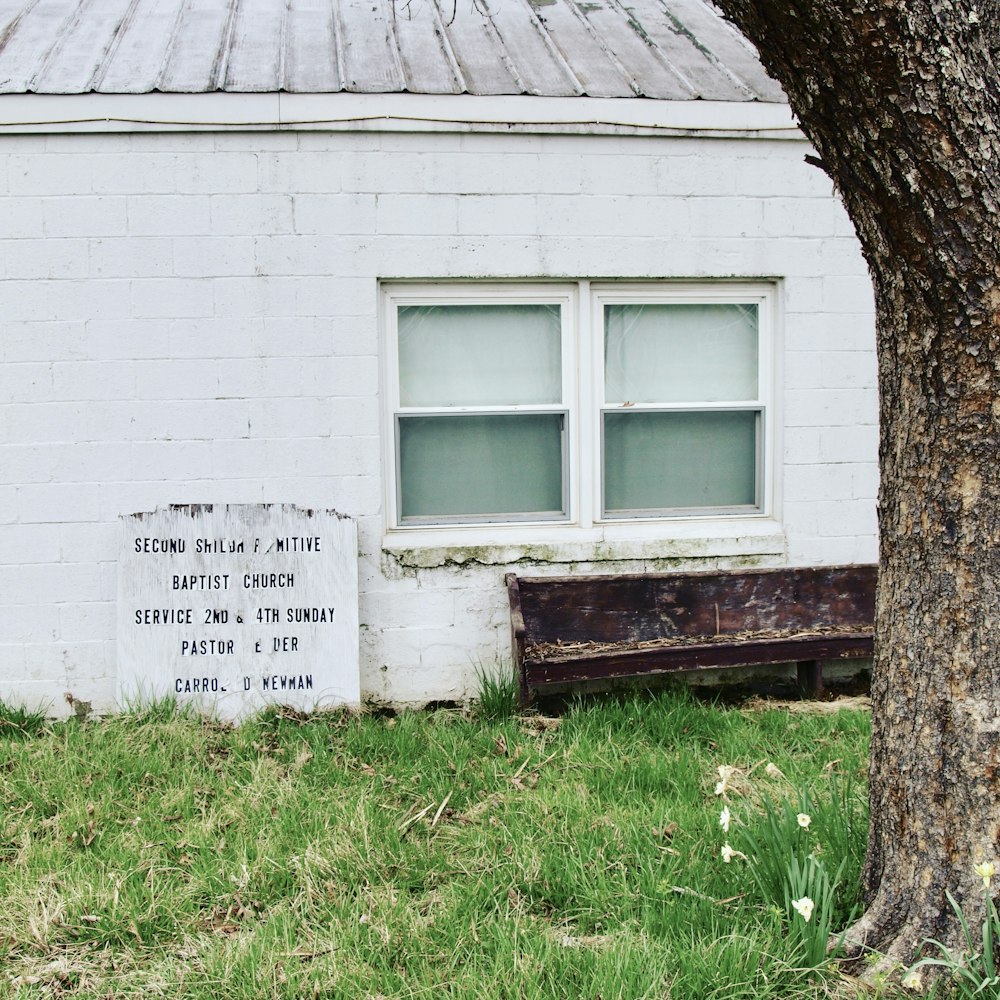 Maison en béton blanc à côté d’un arbre et d’un banc