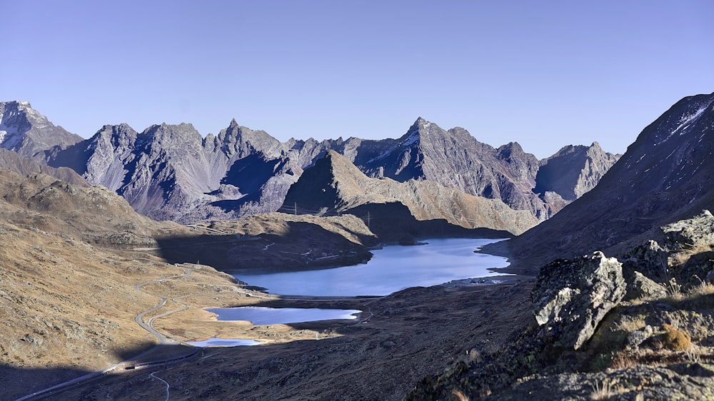 body of water by mountains during daytime