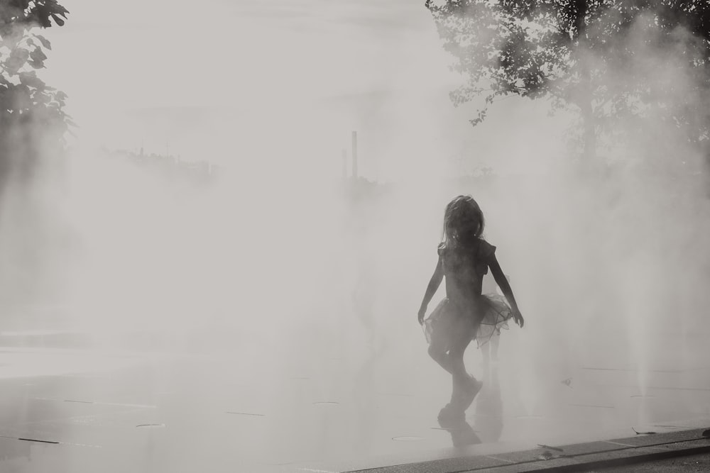 a woman is walking through a fountain of water