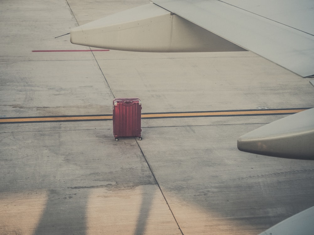 red hard shell luggage by an airplane wing