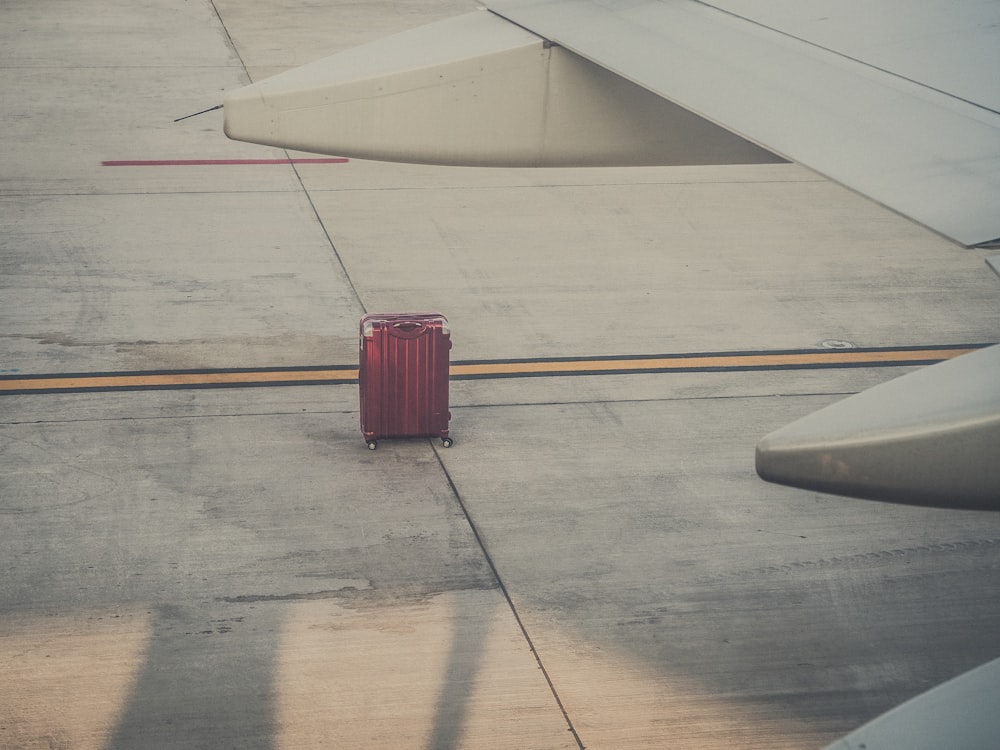 Rotes Hartschalengepäck an einem Flugzeugflügel