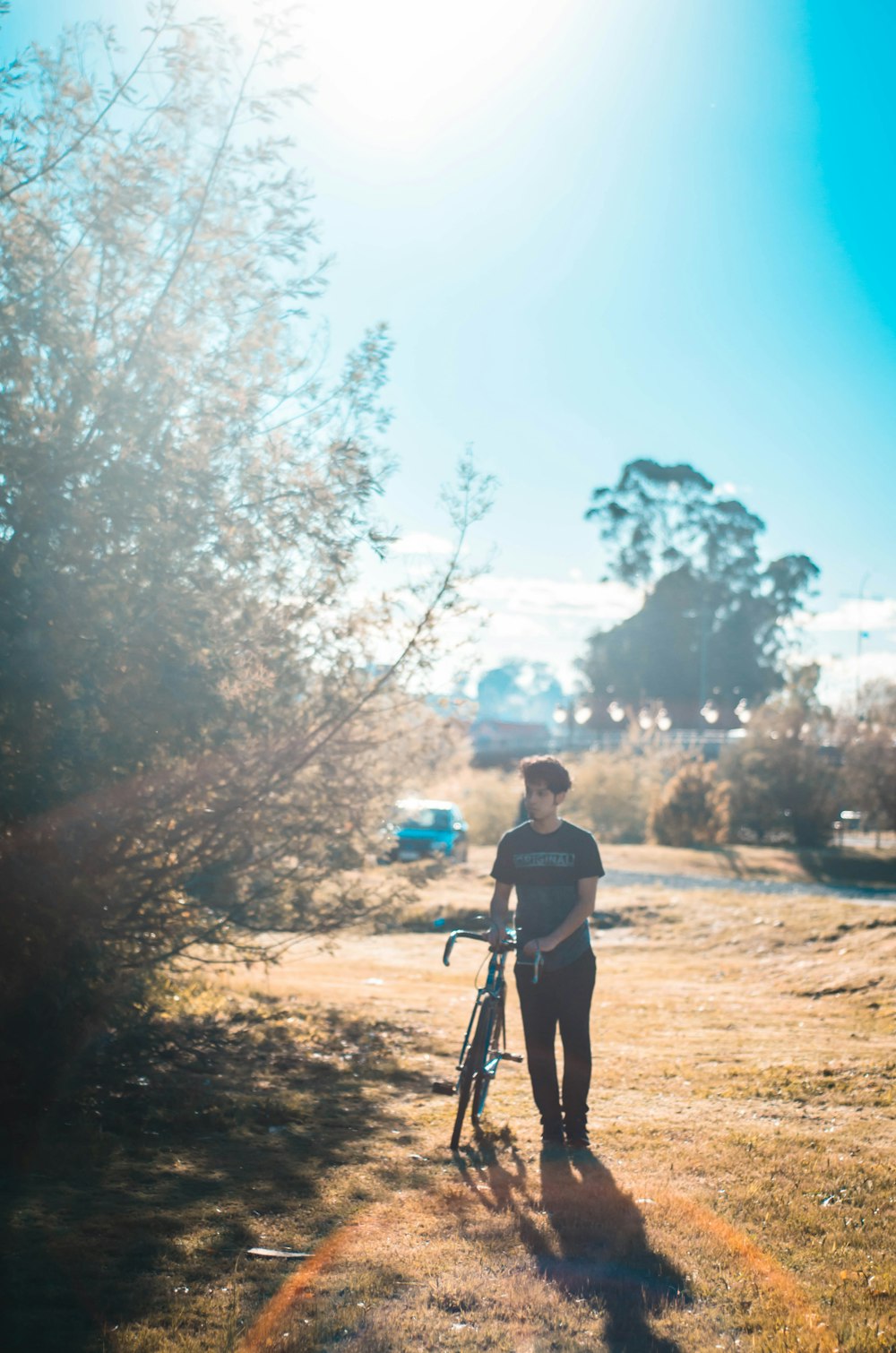 uomo in piedi accanto alla bici e all'albero